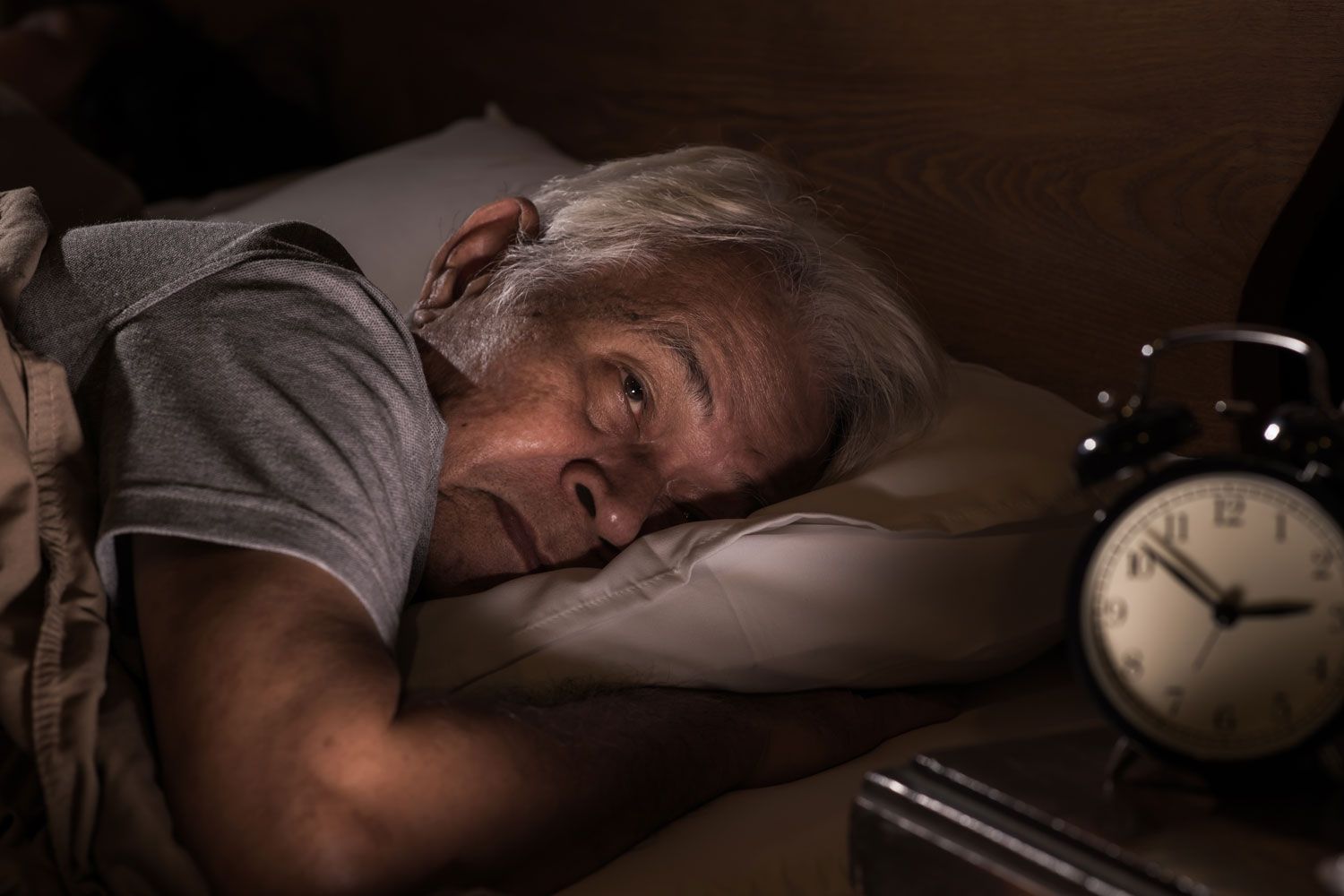man in bed wth alarm clock